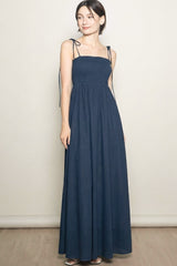 woman wearing a navy blue maxi dress with strap details and a smocked bodice