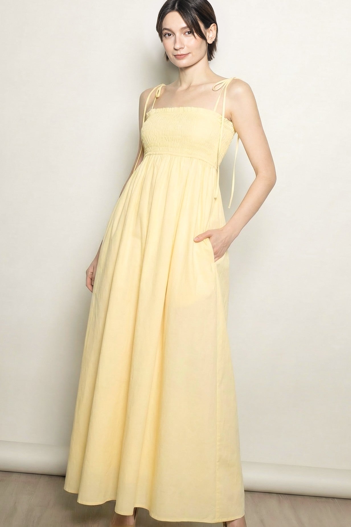 woman wearing a yellow maxi dress with adjustable straps and side pockets