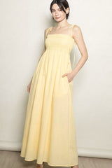 woman wearing a yellow maxi dress with adjustable straps and side pockets