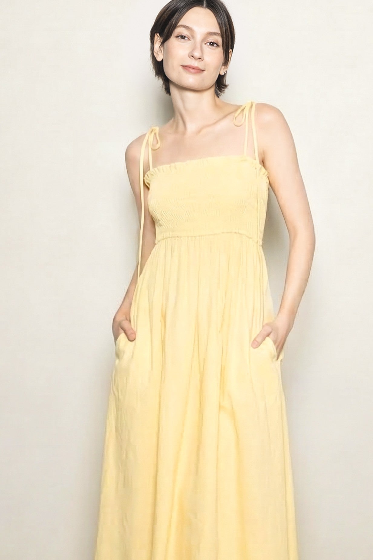 woman wearing a yellow maxi dress with adjustable straps and pockets