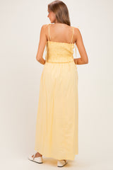 woman wearing a yellow maternity maxi dress with a smocked back and tie straps