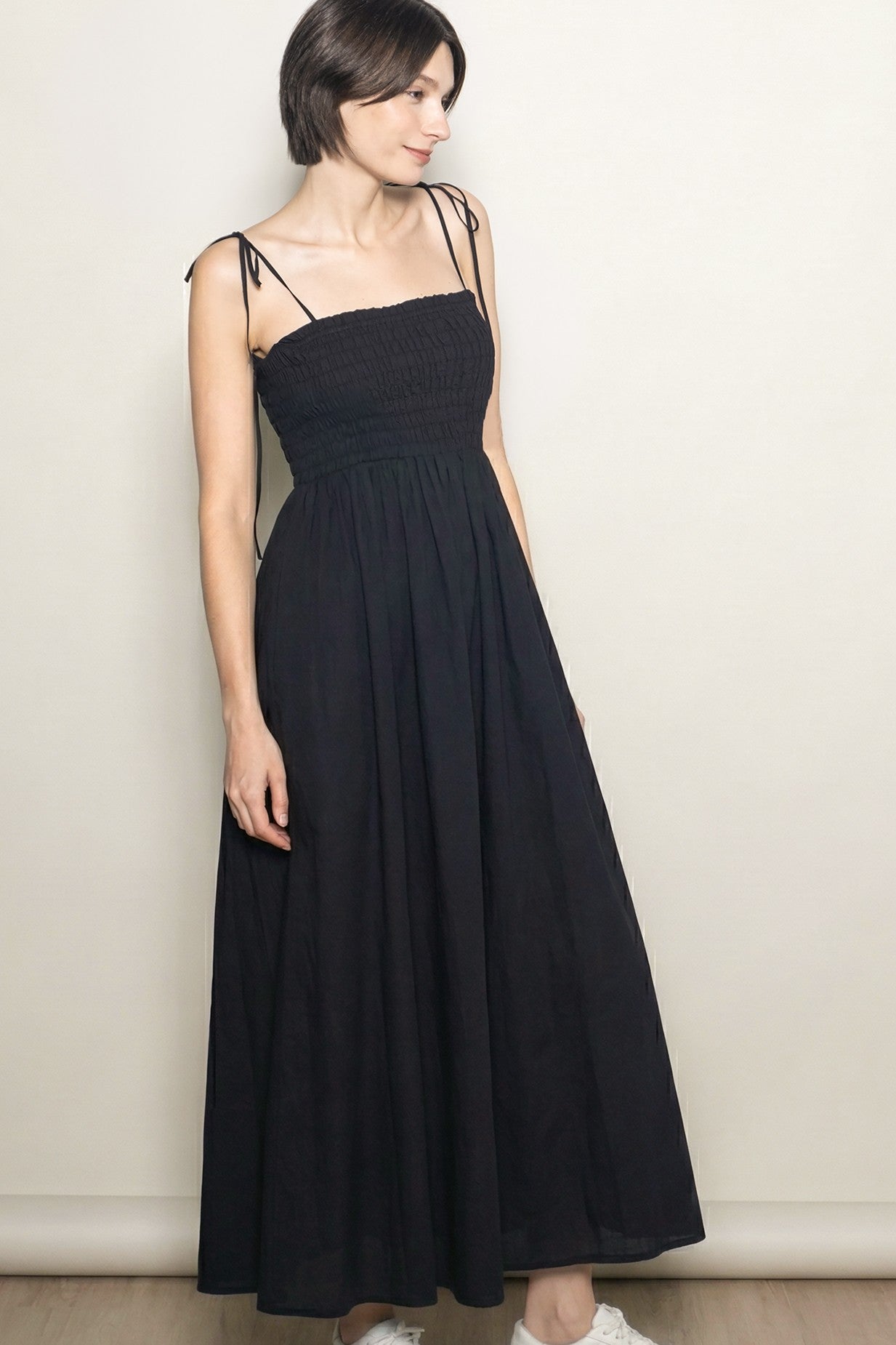 woman wearing a black maxi dress with smocked bodice and thin adjustable straps