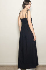 woman wearing a black maxi dress with adjustable straps and a smocked bodice, shown from the back