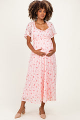 woman wearing a pink floral maternity dress with short flutter sleeves and a baby bump visible