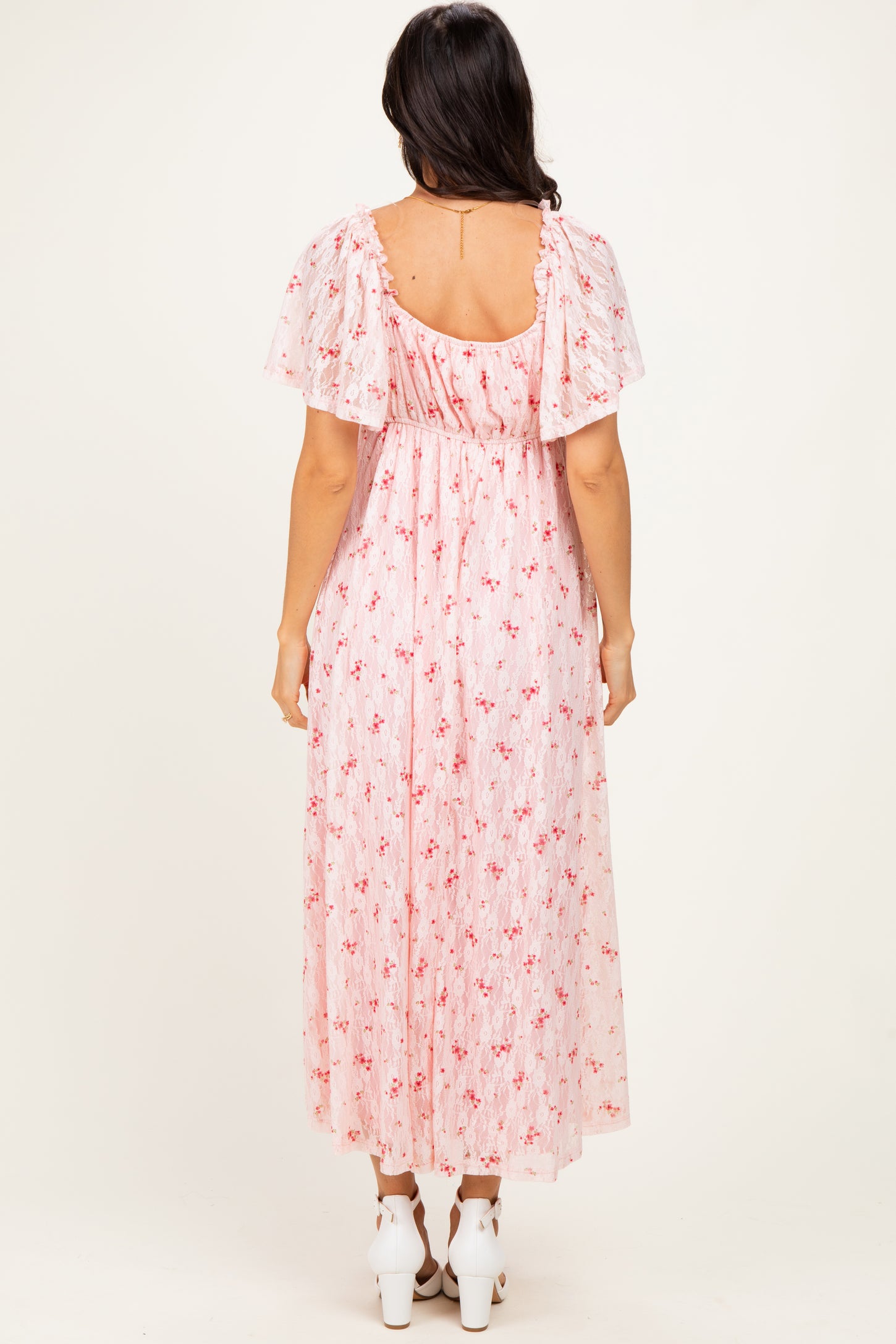 woman wearing a pink floral maxi dress with flutter sleeves, showing the back view and a flowy silhouette