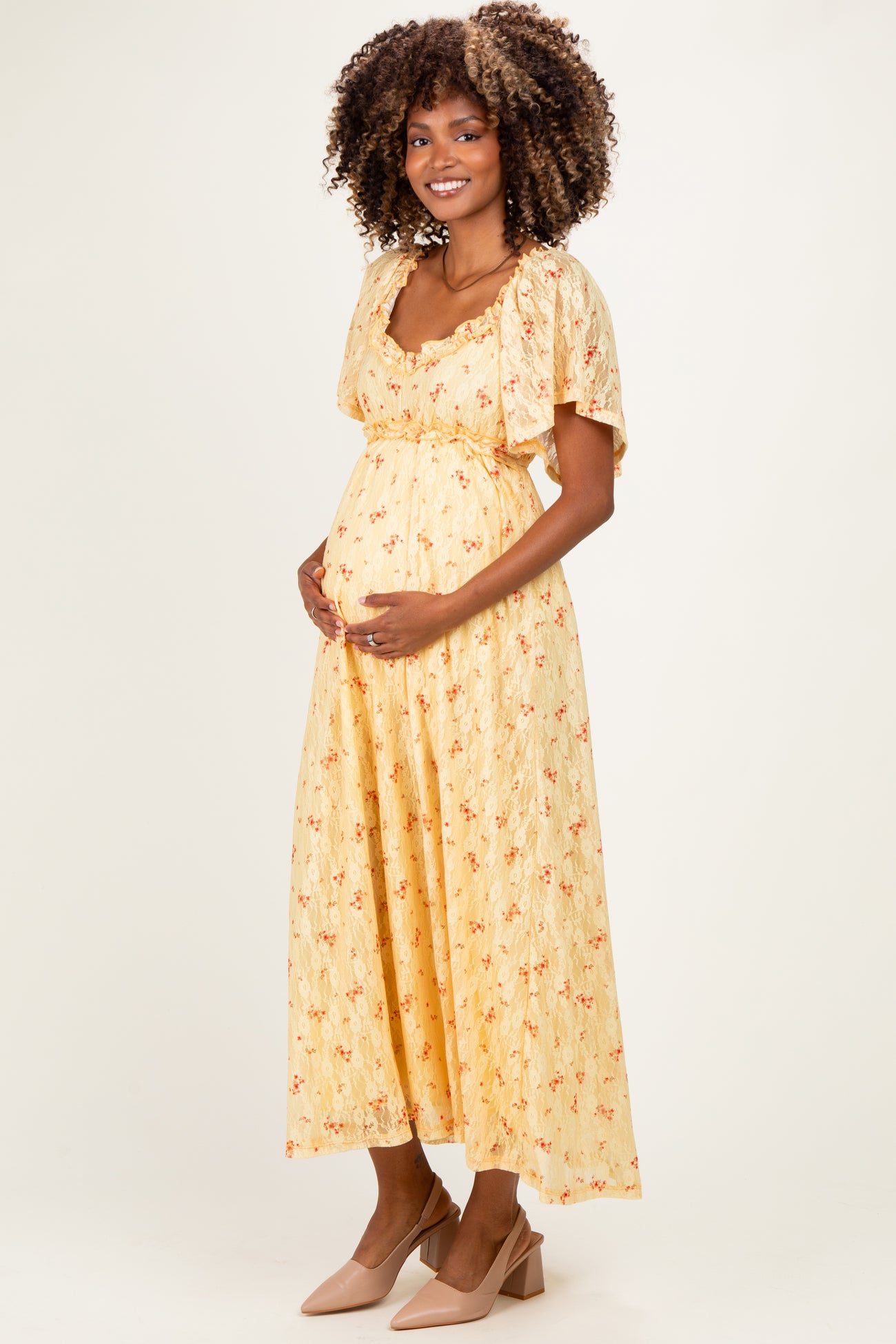 woman wearing a yellow floral maternity dress with short sleeves and holding her baby bump