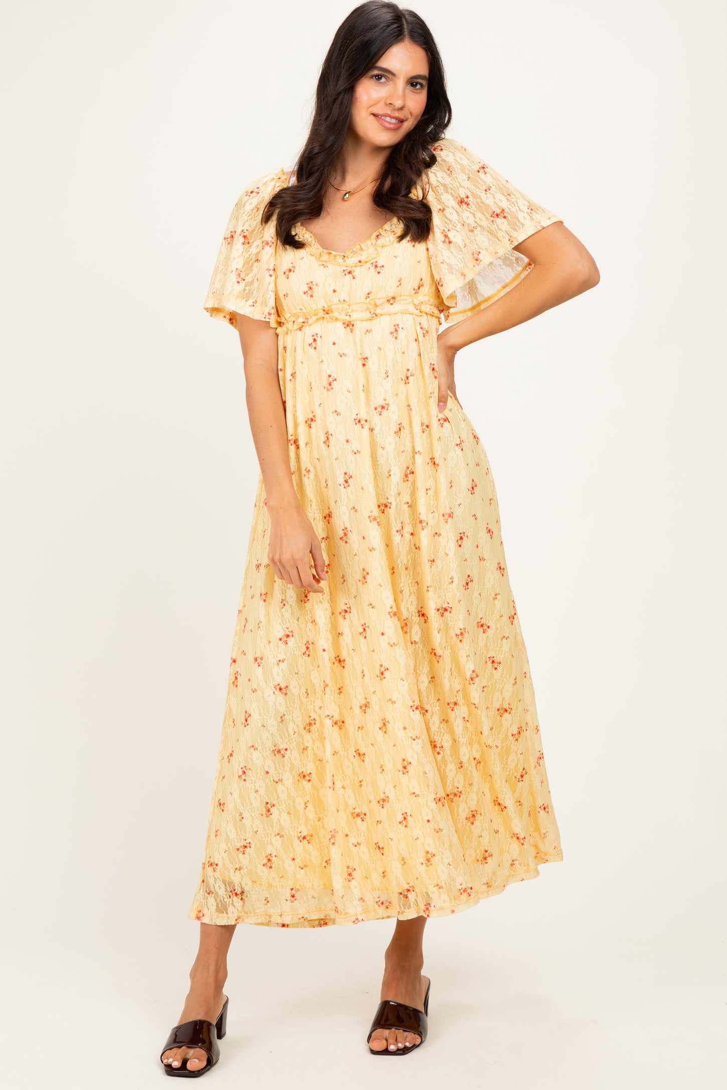 woman wearing a yellow floral maxi dress with flutter sleeves and a layered design, standing against a neutral background