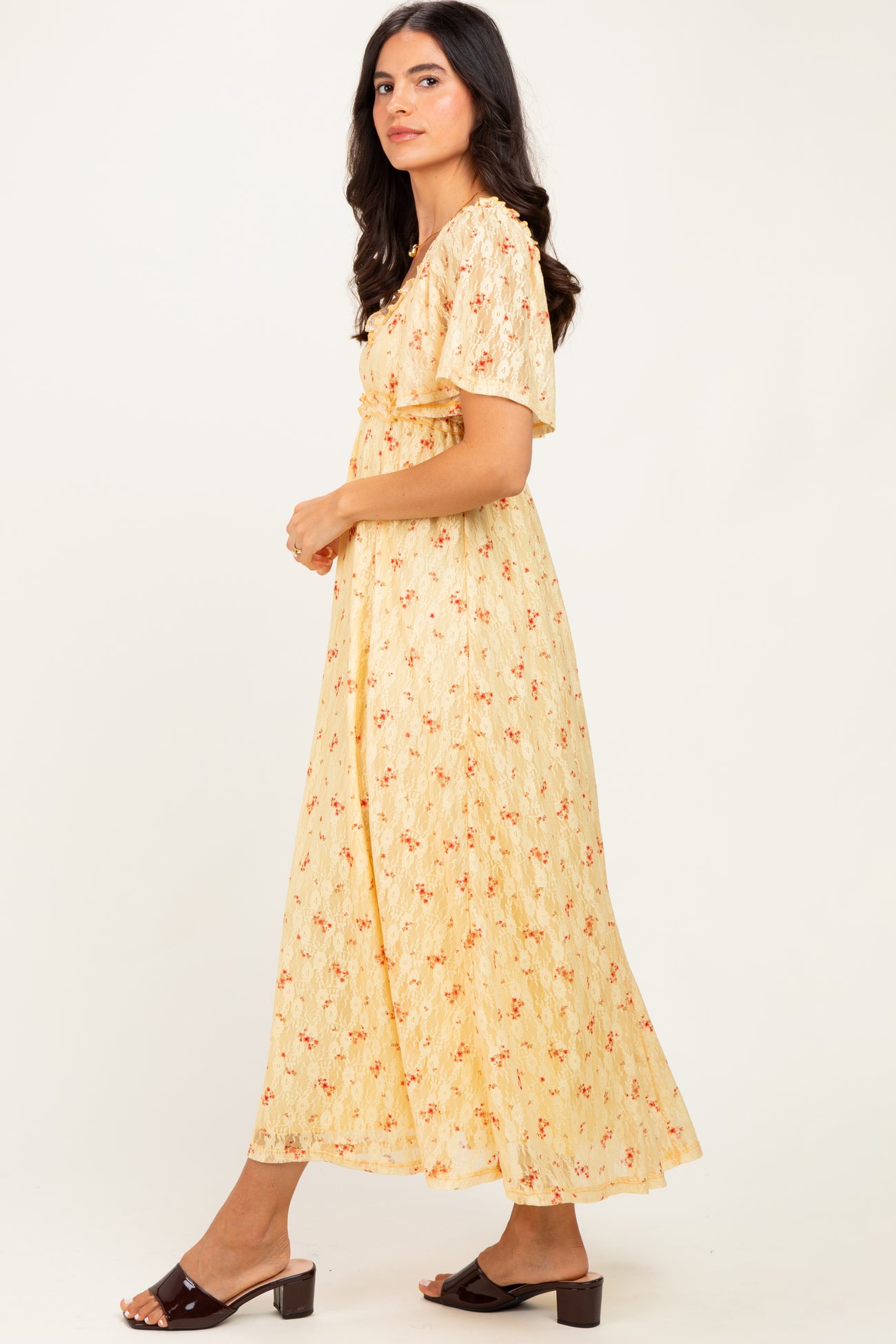 woman wearing a yellow floral maxi dress with short sleeves and a cinched waist, standing in profile