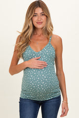 woman wearing a teal maternity tank top with white floral print and holding her baby bump