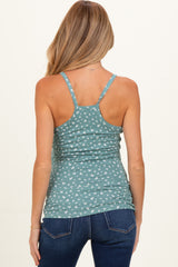 woman wearing a green maternity tank top with a white floral pattern, seen from the back, paired with dark blue jeans