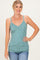 woman wearing a teal floral print camisole top with thin straps and a fitted style, paired with blue jeans