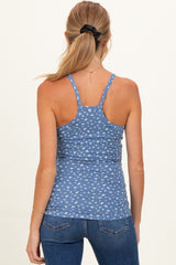 woman wearing a blue maternity tank top with a small white print, showing her back, paired with dark jeans