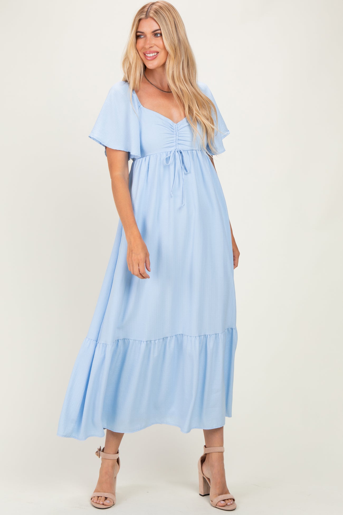 woman wearing a light blue maxi dress with flutter sleeves and a cinched waist detail