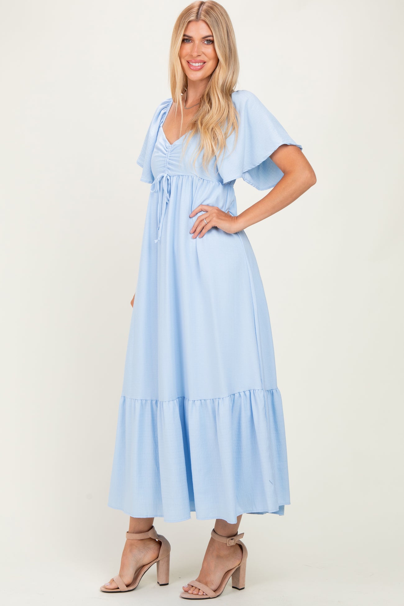 woman wearing a light blue maxi dress with flutter sleeves and a tie waist detail
