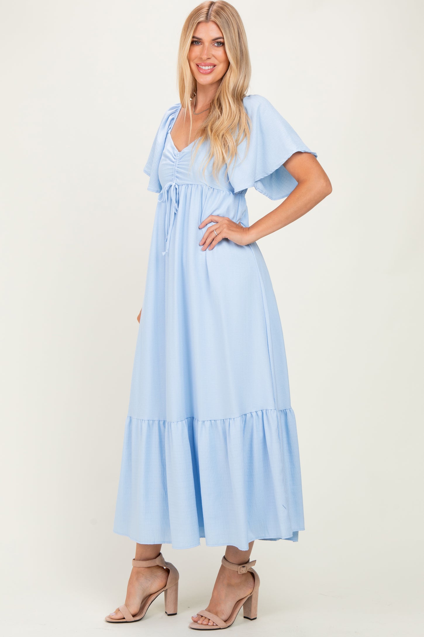 woman wearing a light blue maxi dress with flutter sleeves and a tie waist detail