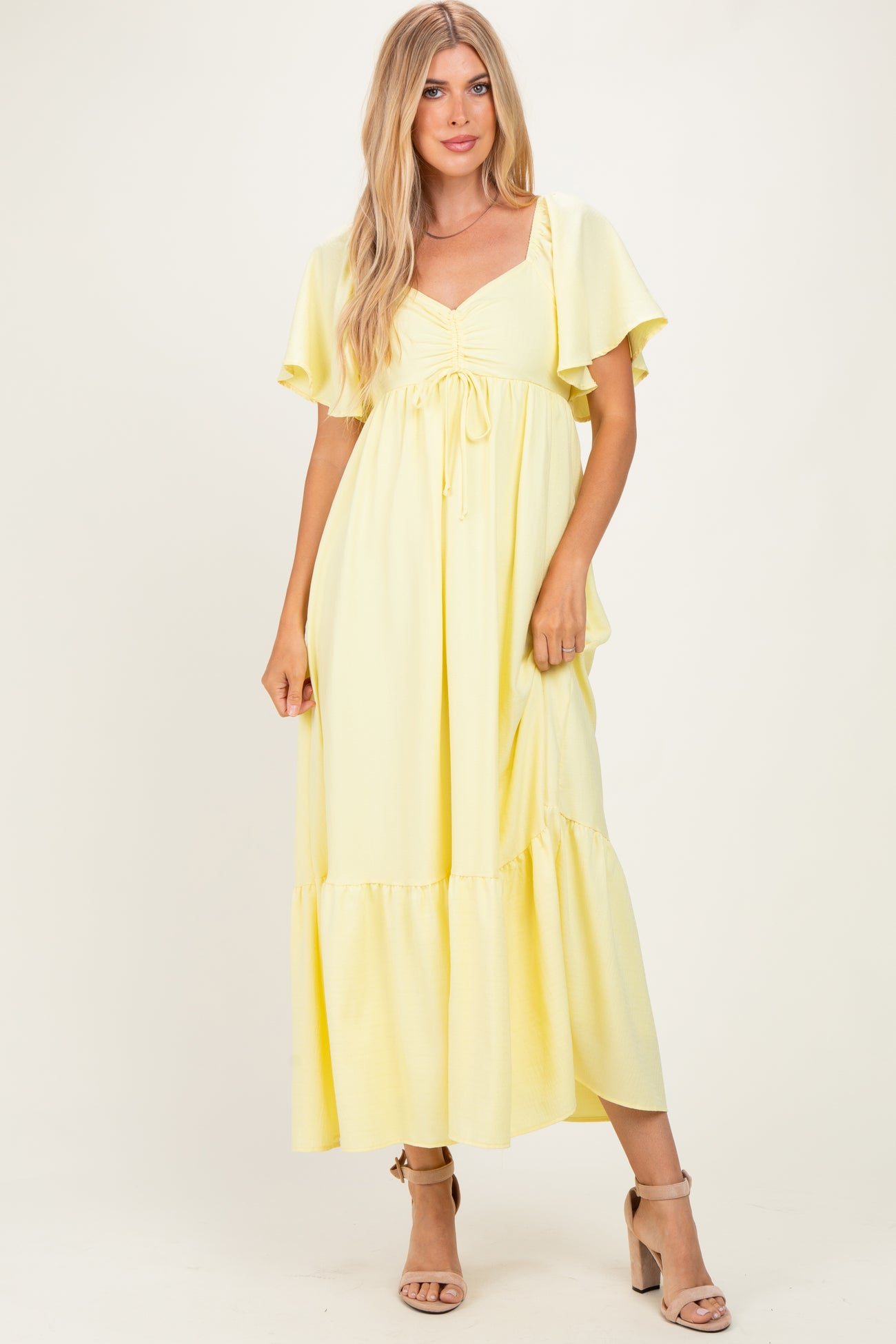 woman wearing a yellow maxi dress with flutter sleeves and a tie detail at the bust