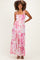 woman wearing a pink and white tiered maternity dress with smocked bodice and adjustable straps, showcasing her baby bump