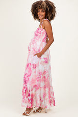 woman wearing a pink tie-dye maternity maxi dress with adjustable straps and pockets, showing her baby bump