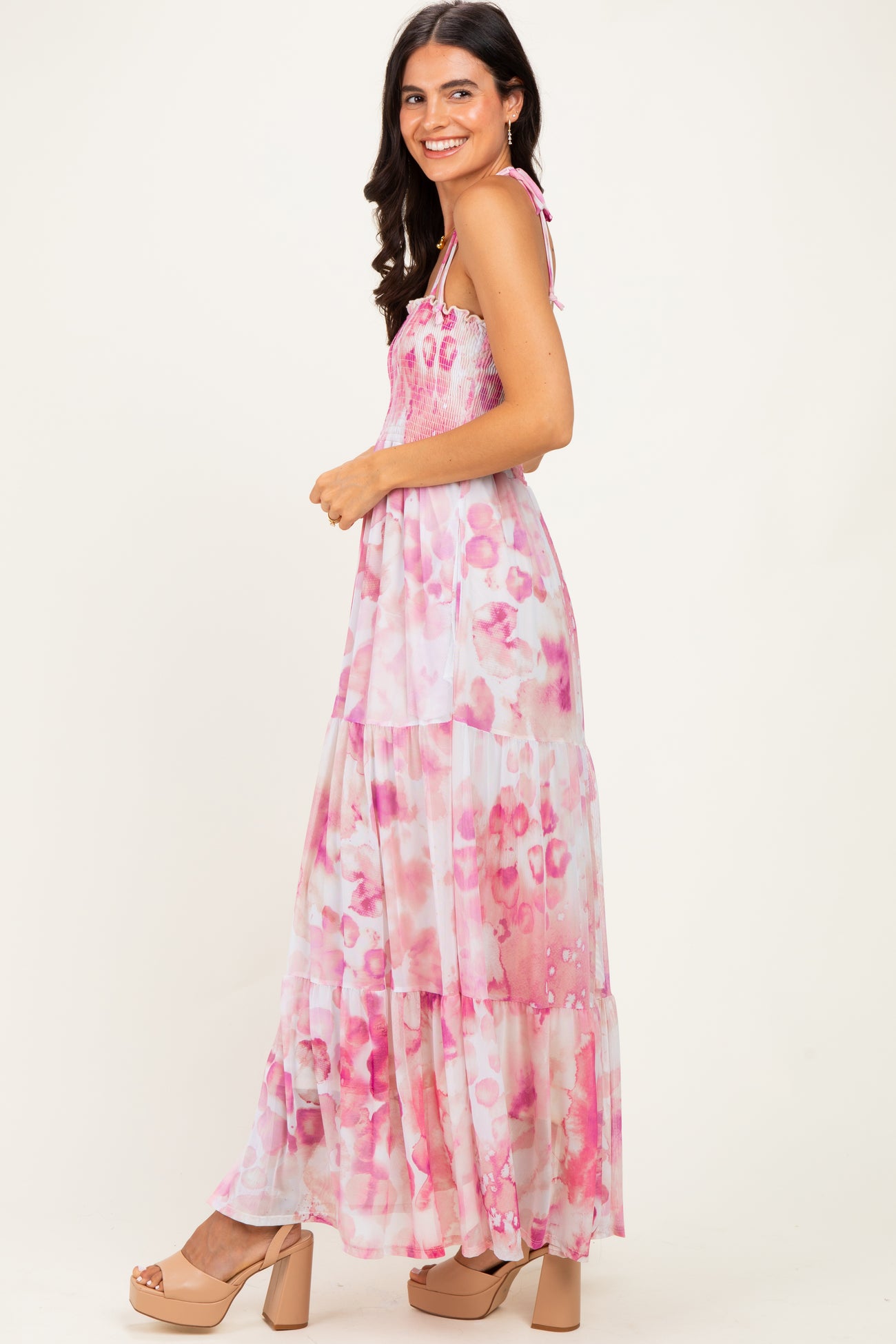 woman wearing a pink tie-dye maxi dress with smocked bodice and tiered skirt, smiling against a neutral background