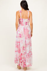 woman wearing a back view of a pink floral maxi dress with adjustable straps and tiered design