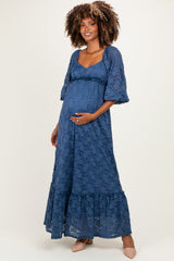 woman wearing a dark blue lace maternity maxi dress with puff sleeves and a baby bump visible