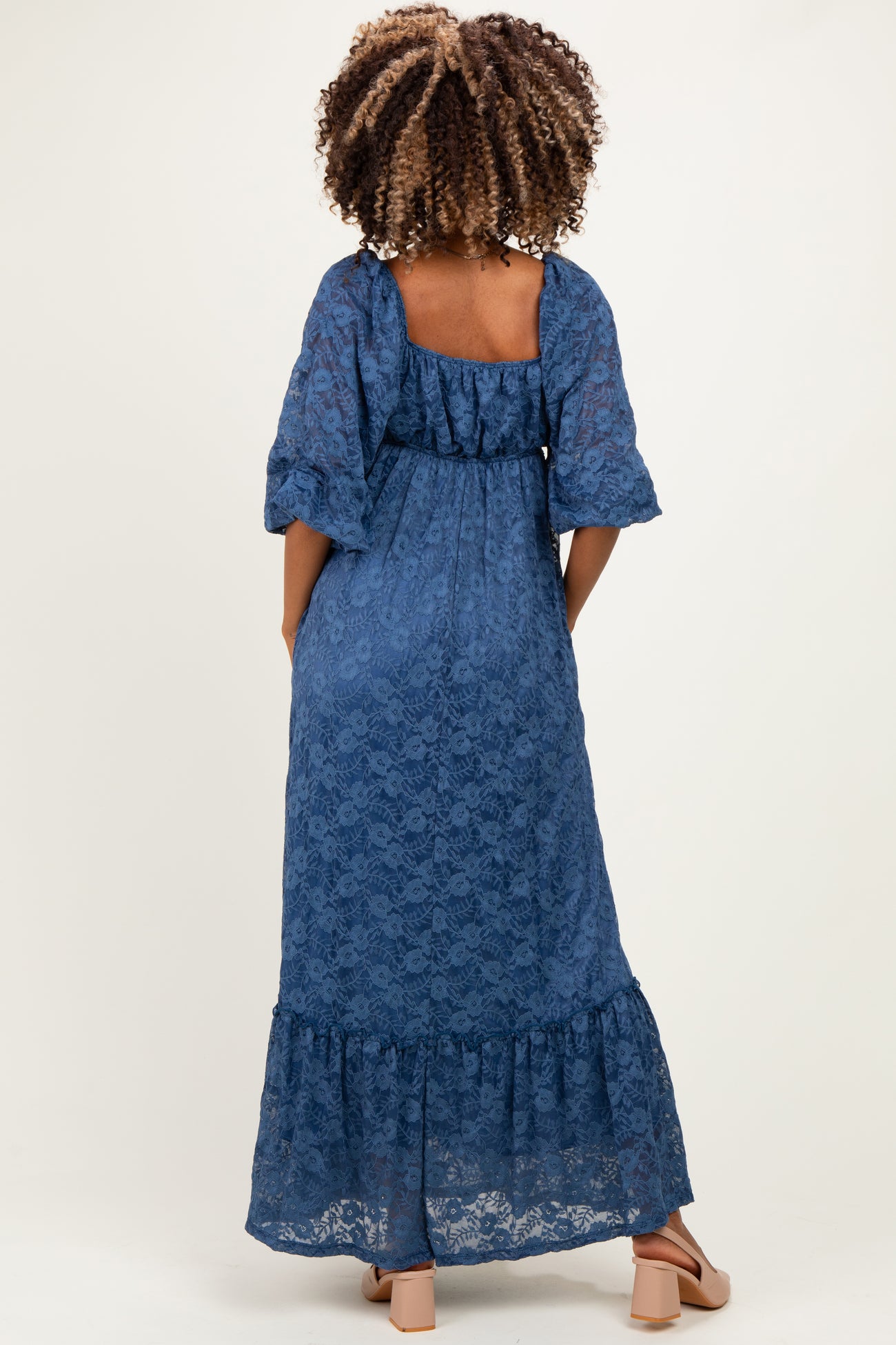 woman wearing a blue lace maternity maxi dress with three-quarter puff sleeves and a tiered hem