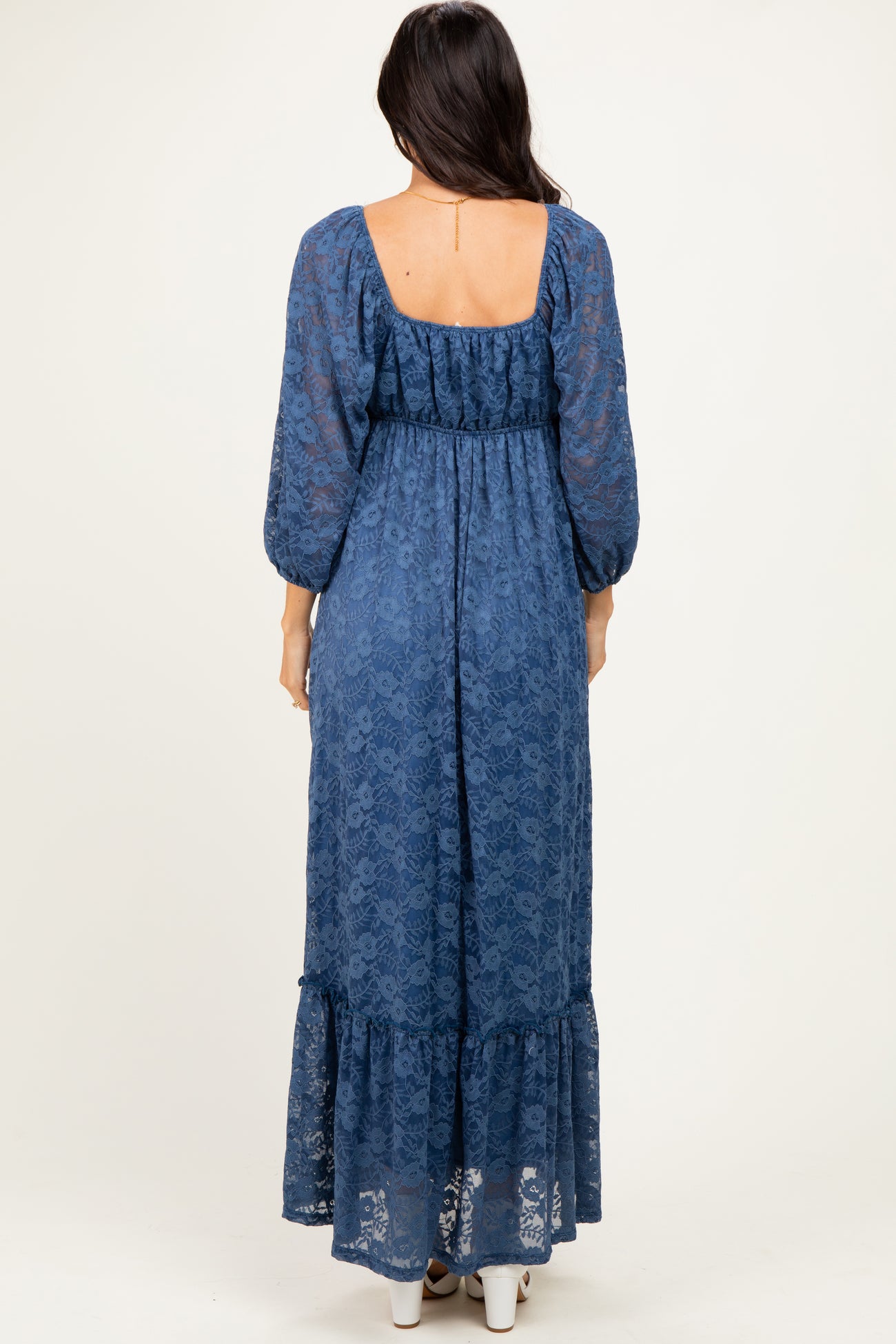 woman wearing a navy blue lace maxi dress with a square neckline and puff sleeves, showing the back view