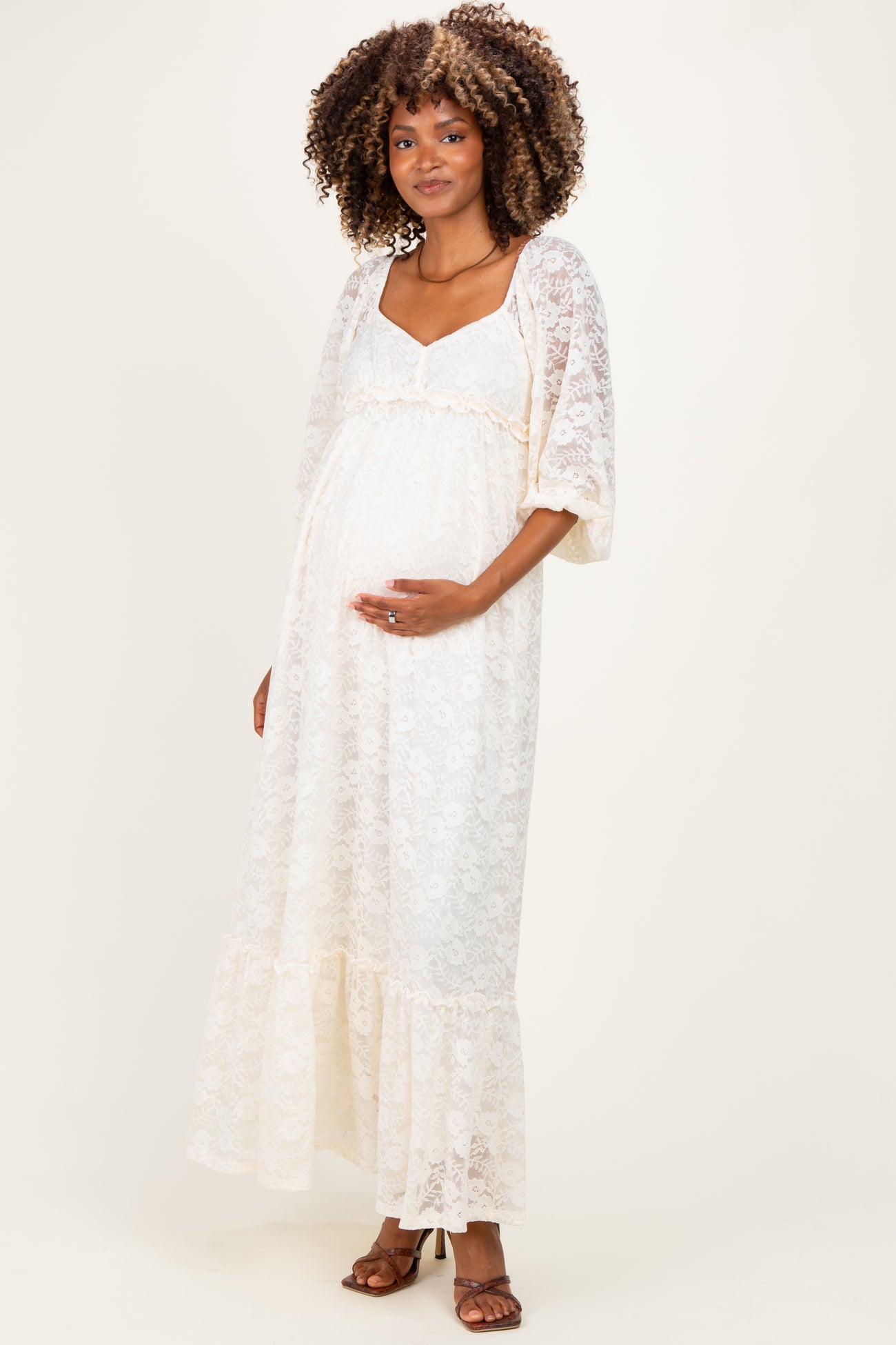 woman wearing a white lace maternity maxi dress with a ruffled hem and a visible baby bump