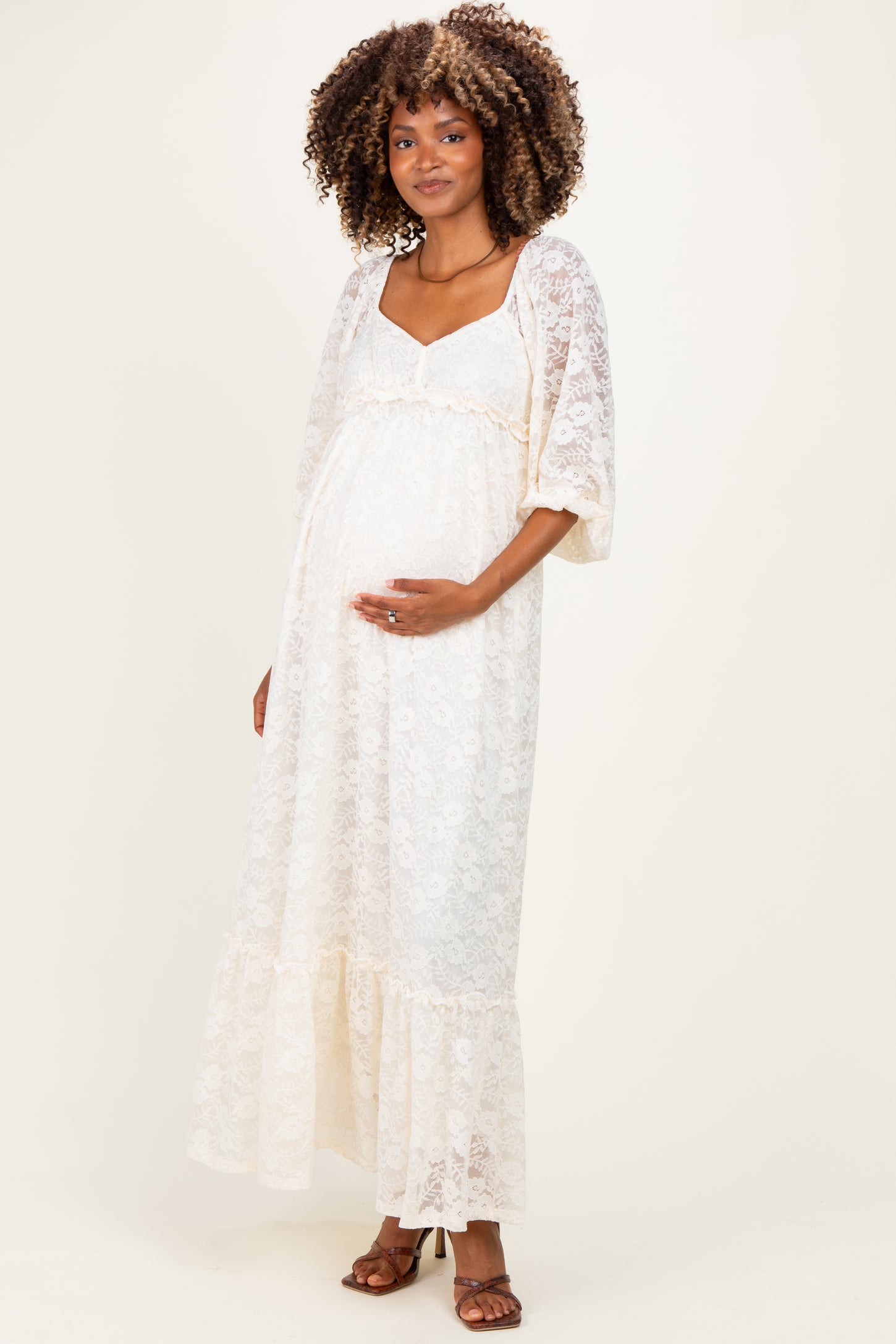 woman wearing a white lace maternity maxi dress with a ruffled hem and a visible baby bump