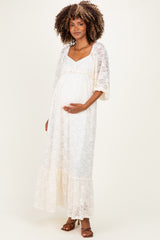 woman wearing a white lace maternity maxi dress with a ruffled hem and a visible baby bump