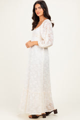 woman wearing a long white lace maxi dress with three-quarter sleeves and a tiered hem