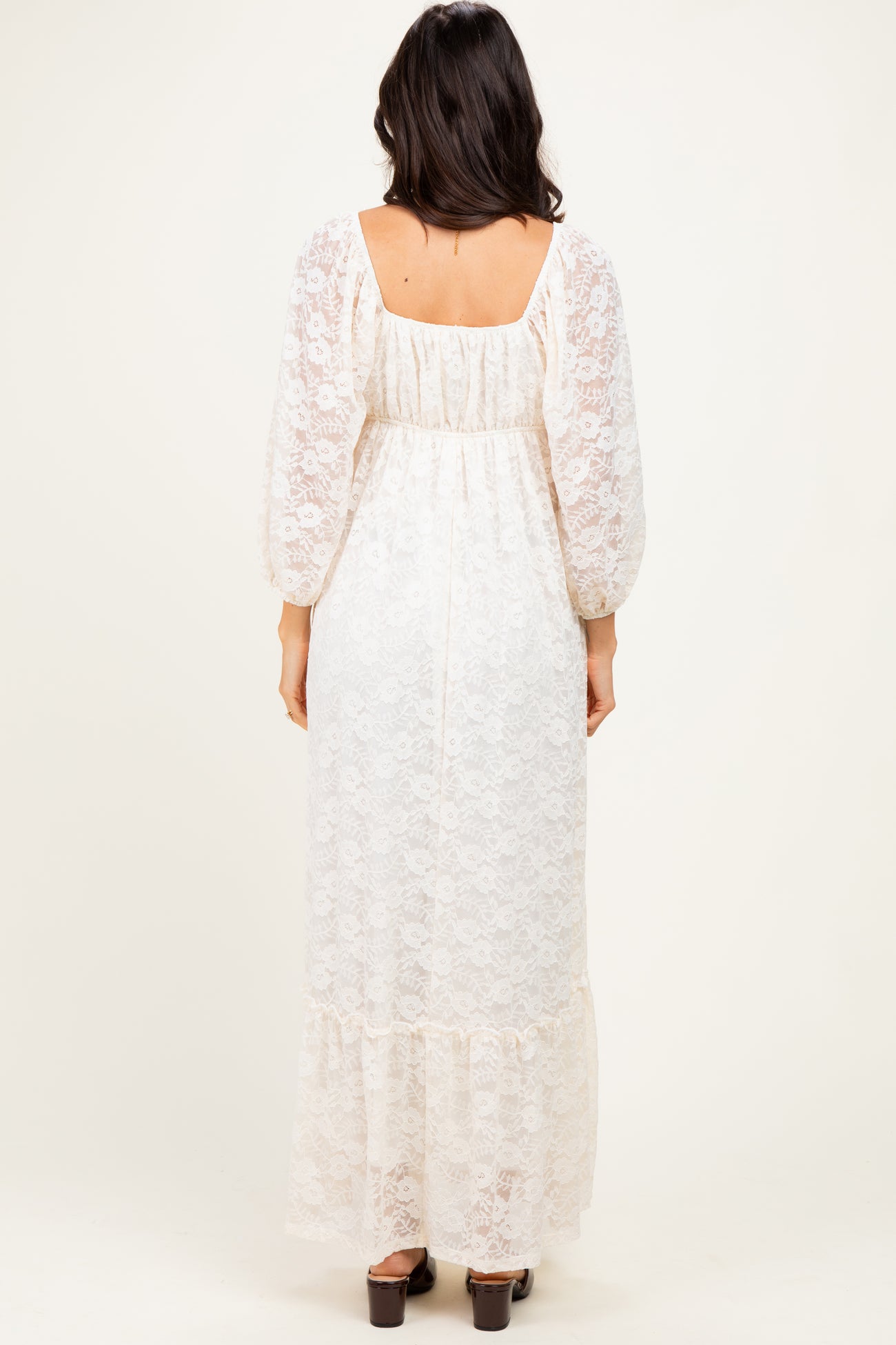 woman wearing a cream lace maxi dress with puff sleeves and a tiered hem, viewed from the back