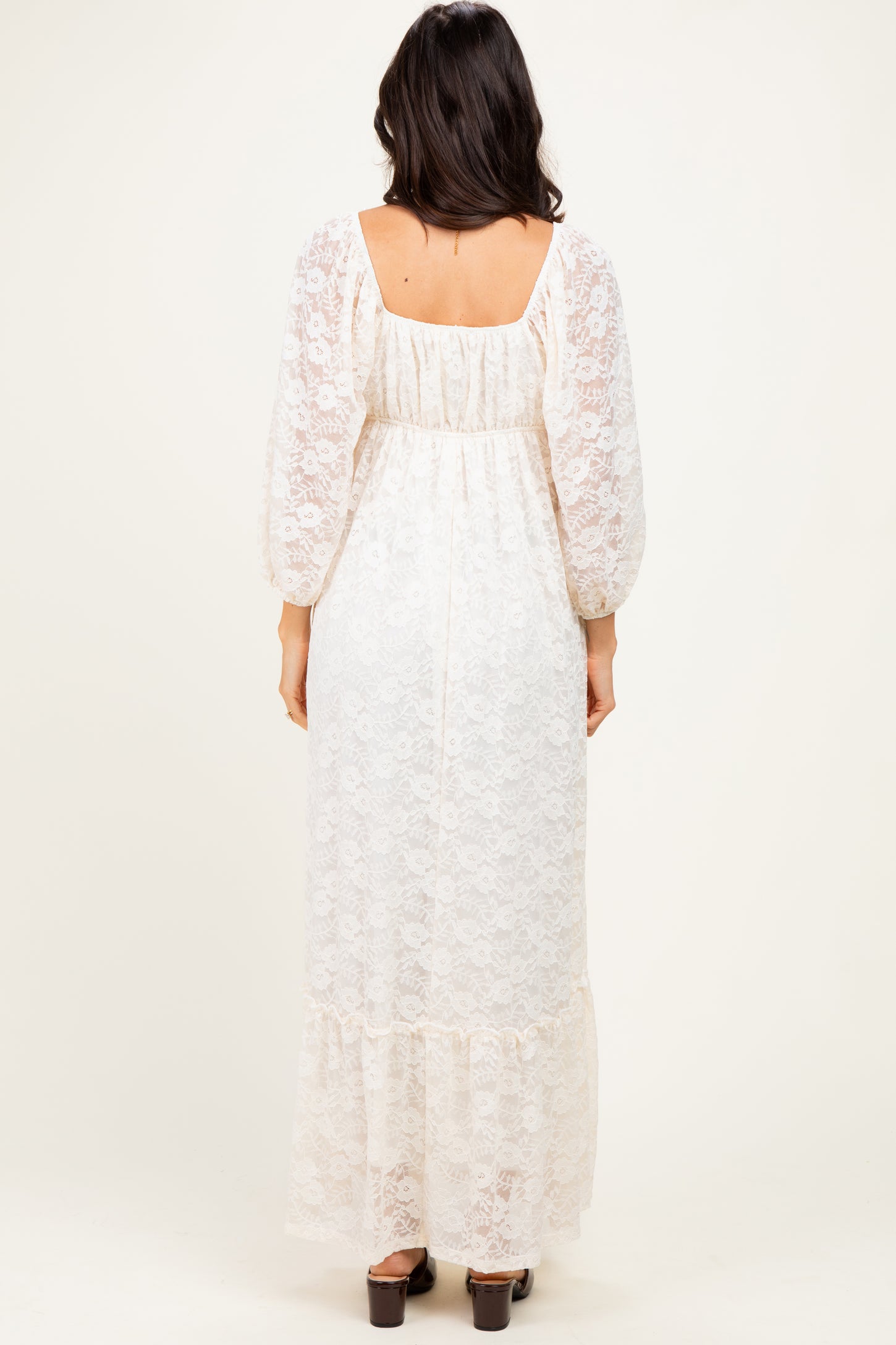 woman wearing a cream lace maxi dress with puff sleeves and a tiered hem, viewed from the back