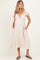 woman wearing a light beige maternity dress with puff sleeves, smocked bodice, and side pockets