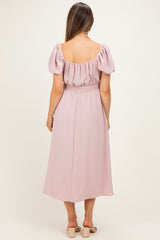 woman wearing a pink maternity dress with puff sleeves and a smocked waist, seen from the back