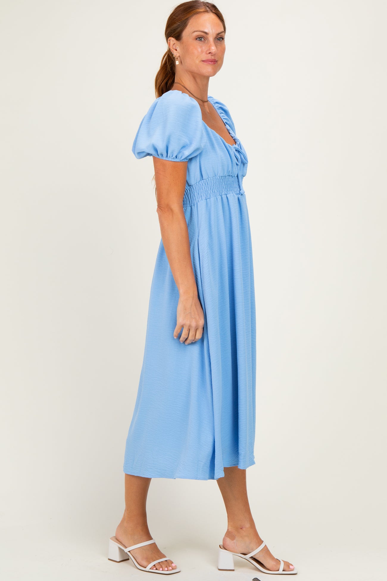 woman wearing a light blue midi dress with puff sleeves and a smocked waist