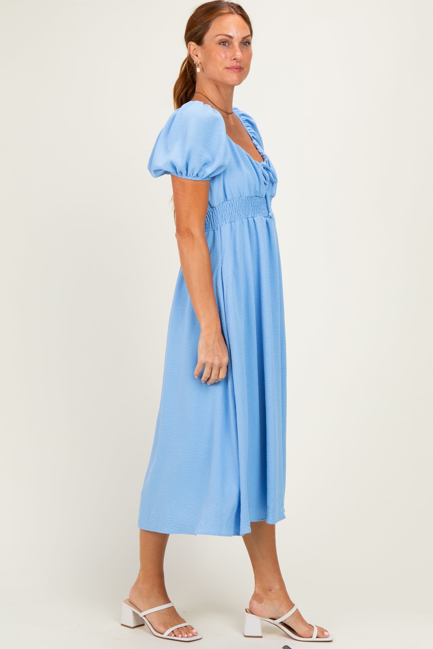 woman wearing a light blue midi dress with puff sleeves and a smocked waist