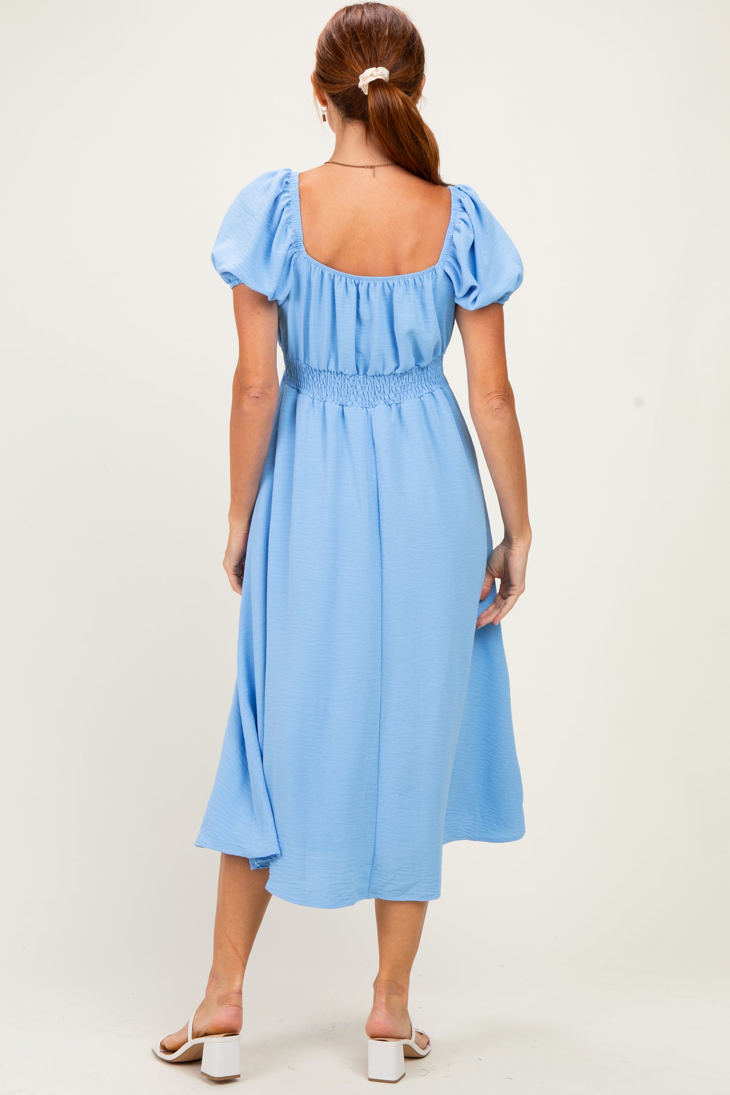 woman wearing a light blue midi dress with puff sleeves and a smocked waist, seen from the back
