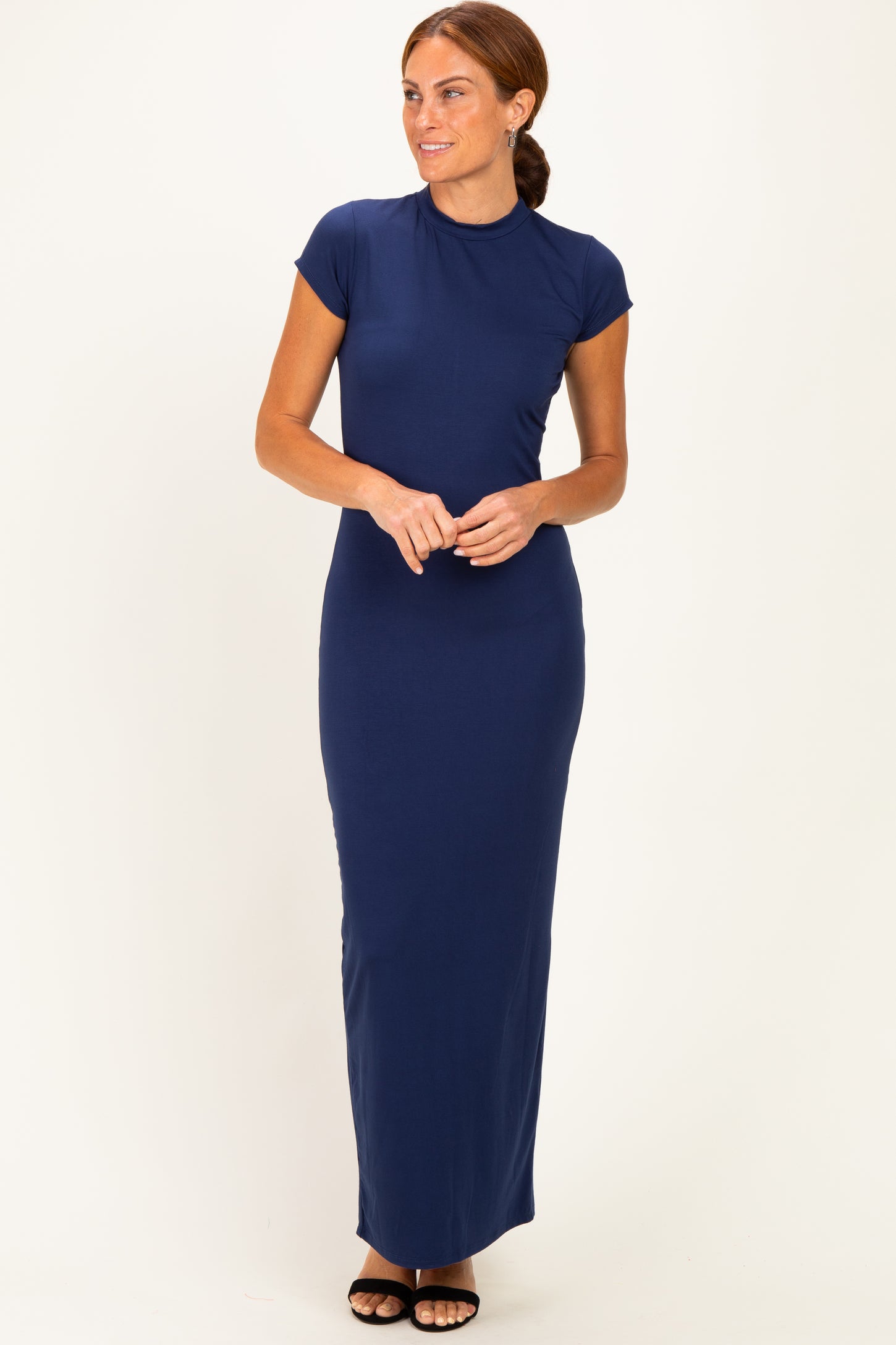 woman wearing a navy blue cap sleeve maxi dress standing with hands clasped at the waist
