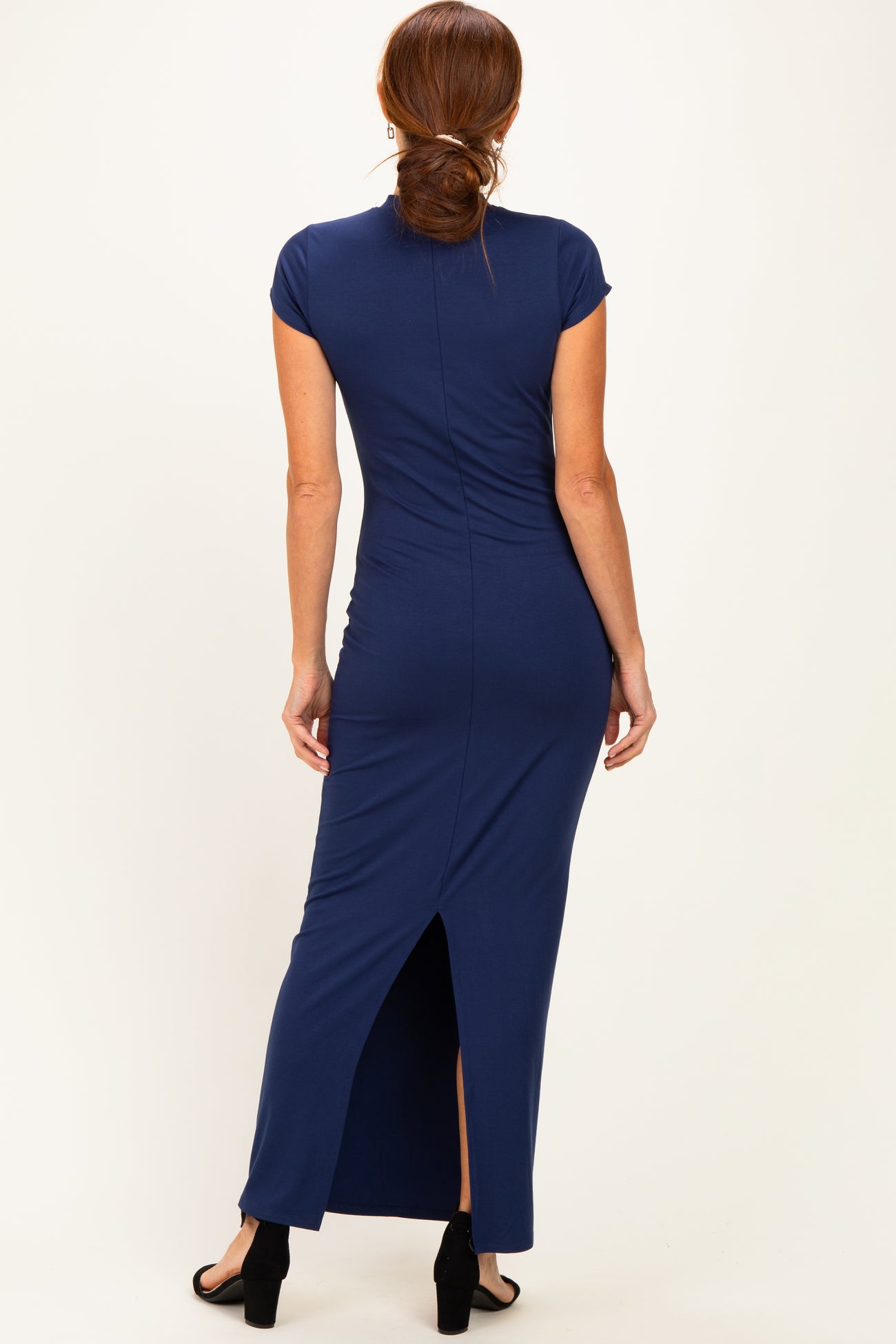 woman wearing a navy blue fitted maxi dress with a back slit and cap sleeves
