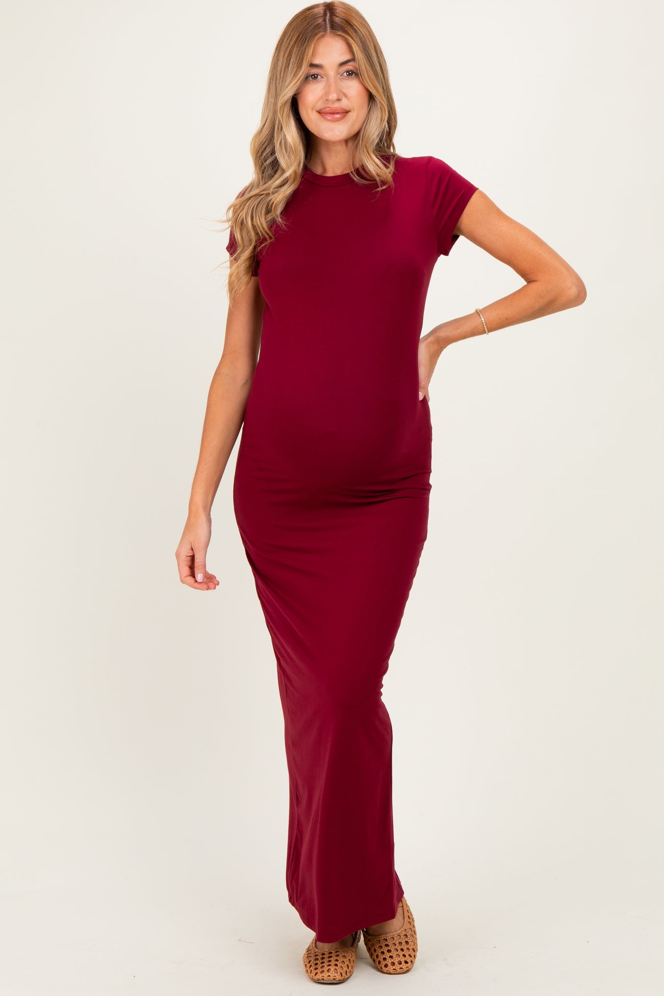 woman wearing a burgundy short sleeve maternity maxi dress, highlighting her baby bump