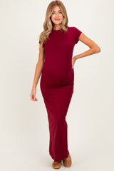 woman wearing a burgundy short sleeve maternity maxi dress, highlighting her baby bump