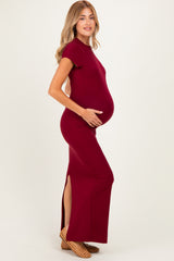 woman wearing a burgundy short sleeve maternity maxi dress with side slits and a visible baby bump