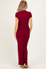 woman wearing a burgundy maternity maxi dress with short sleeves and a back slit, showing her baby bump