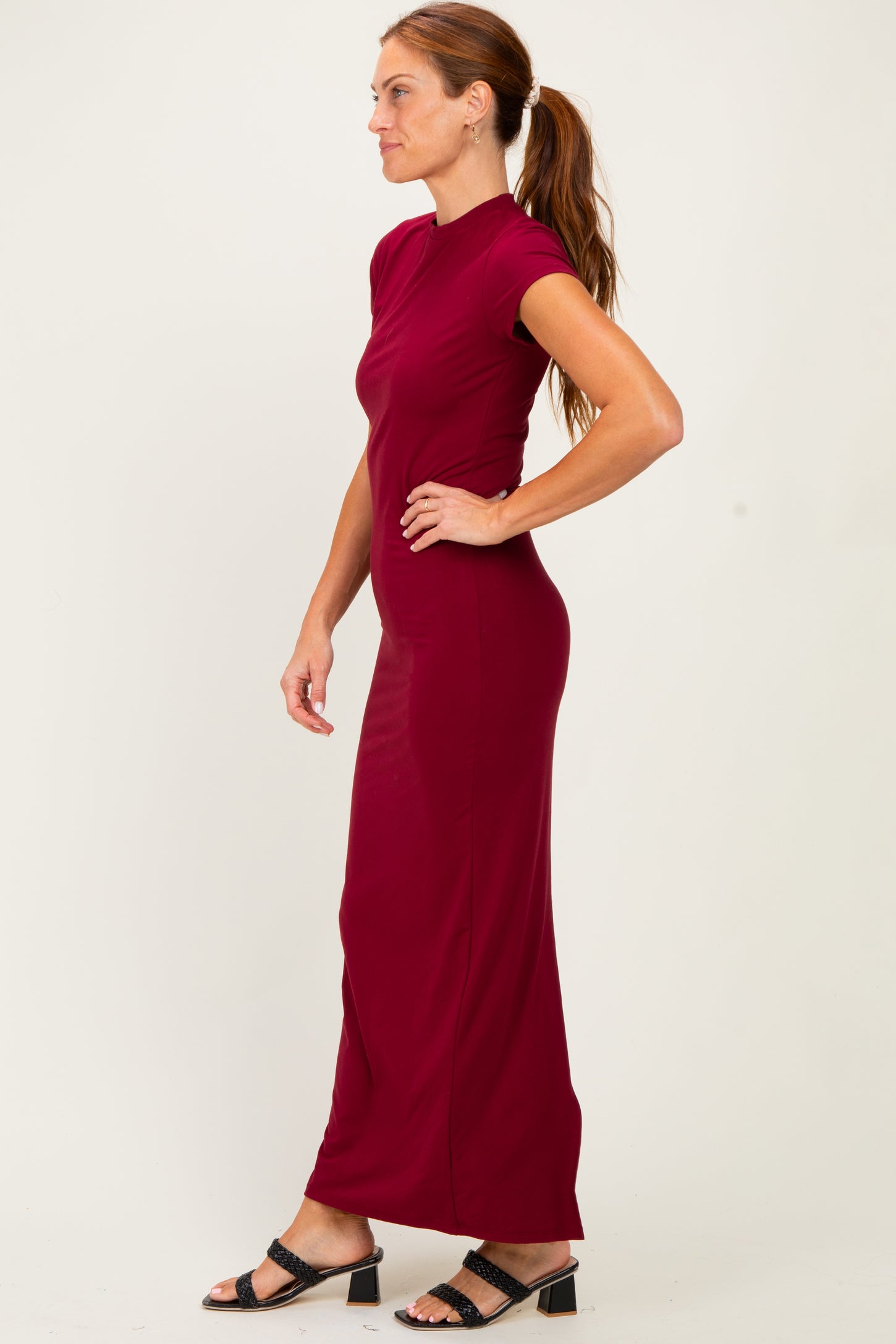 woman wearing a burgundy fitted maxi dress with short sleeves and a high neckline