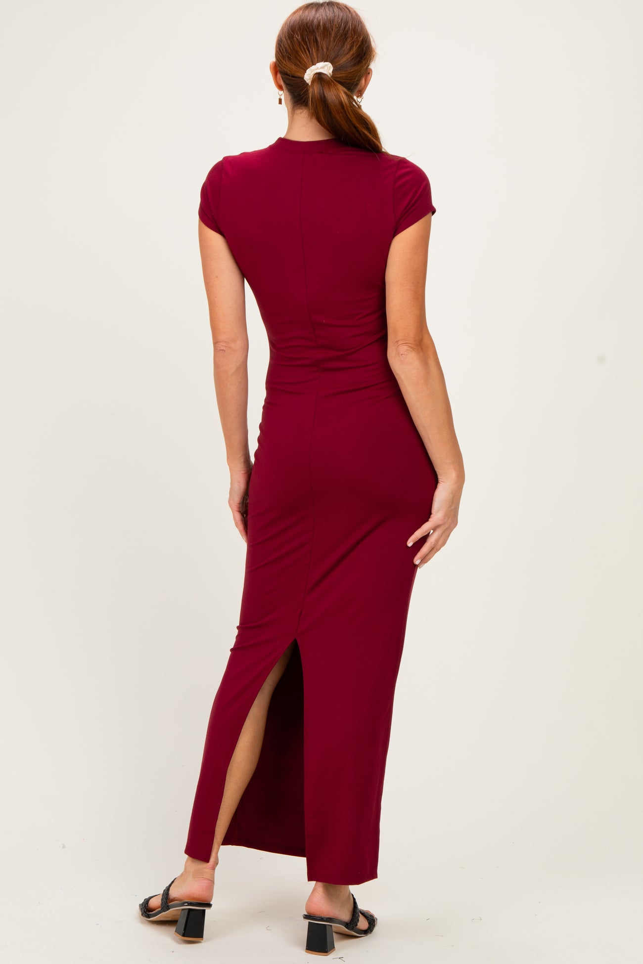 woman wearing a burgundy cap sleeve maxi dress with a side slit, shown from the back