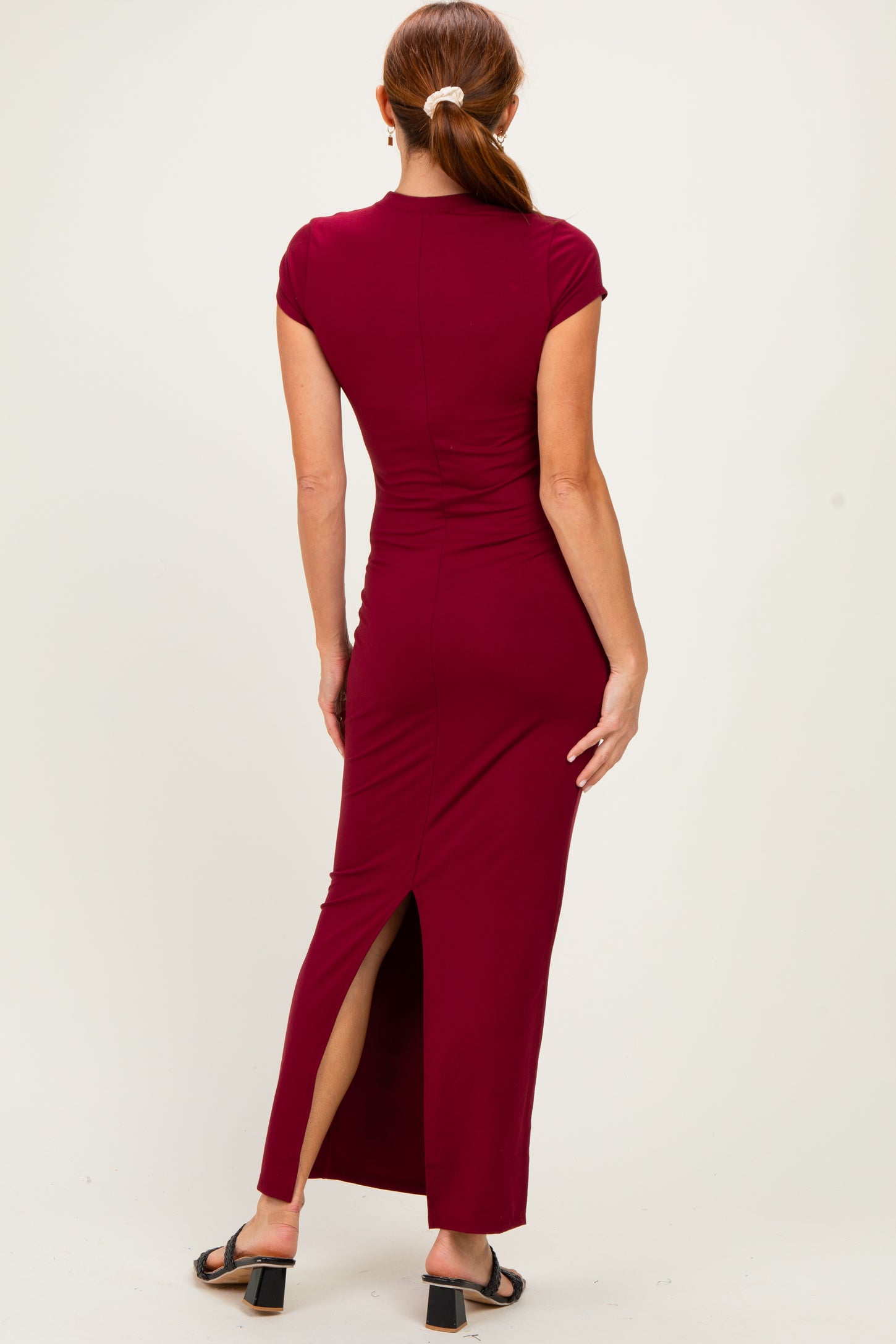 woman wearing a burgundy cap sleeve maxi dress with a side slit, shown from the back