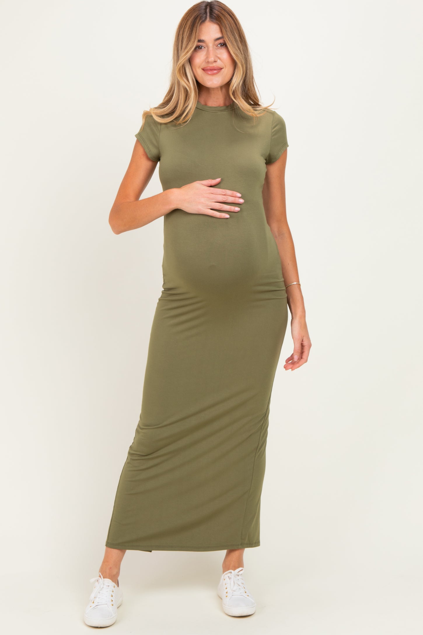woman wearing a fitted olive green maternity maxi dress and holding her baby bump