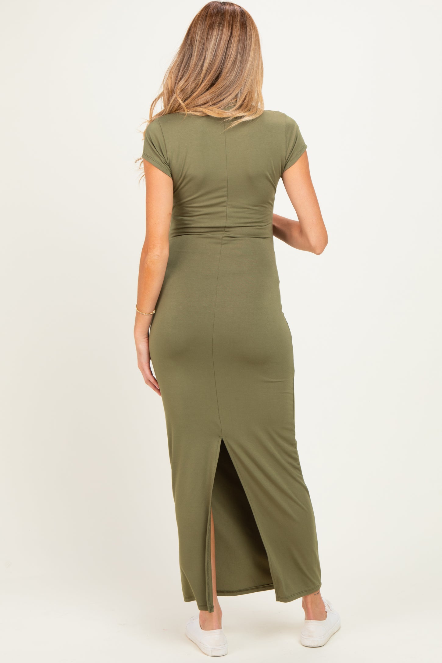 woman wearing an olive green maternity maxi dress with a split at the back