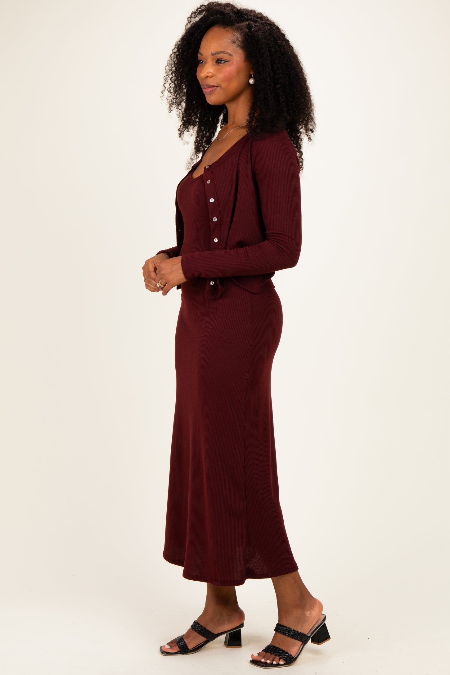woman wearing a burgundy ribbed maxi dress with a matching button-up cardigan and black heeled sandals